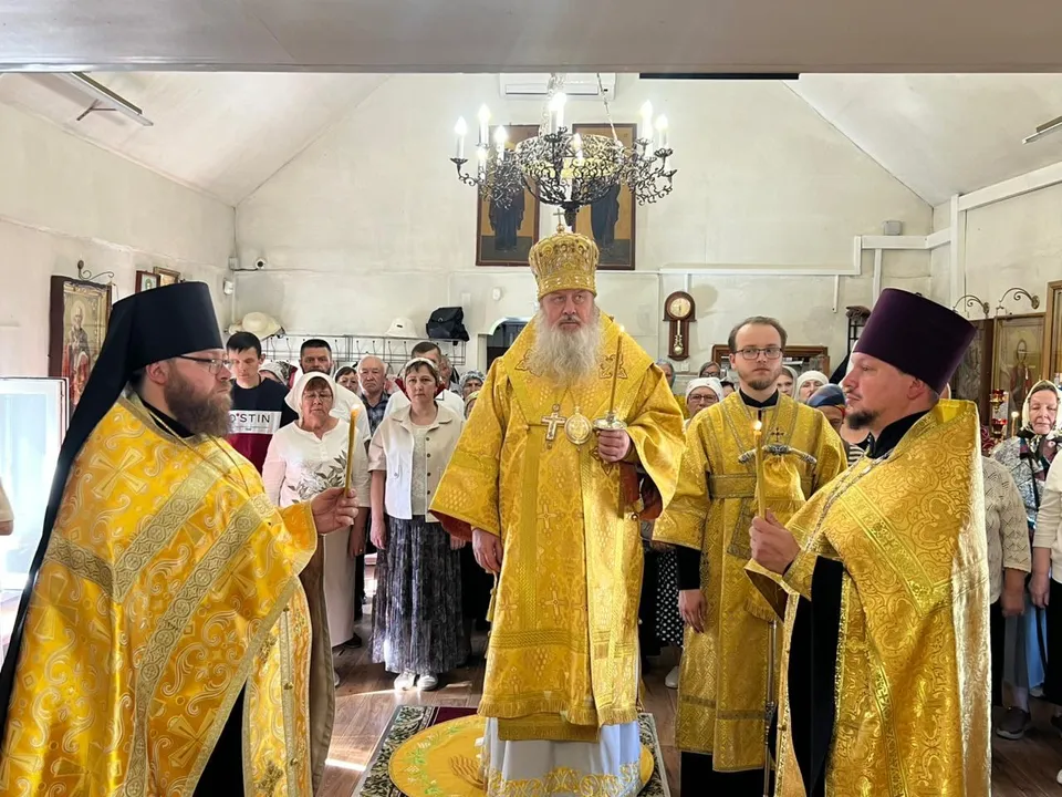 Митрополит в жёлтом облачении с двумя священниками совершают всенощное бдение перед прихожанами в простом храме